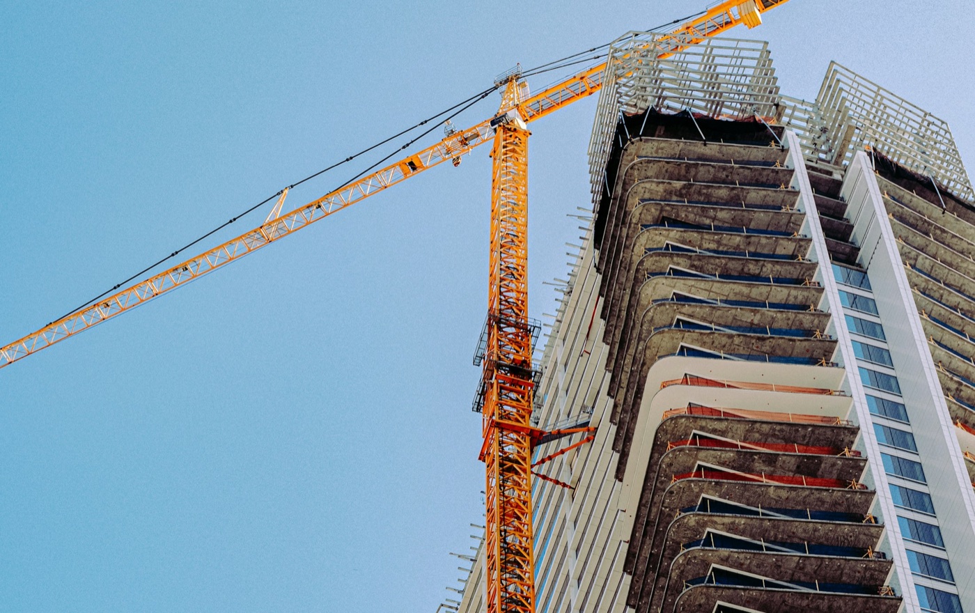 High-rise building under construction beside an orange tower crane