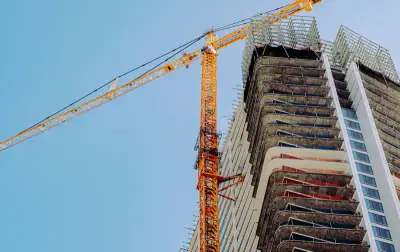 High-rise building under construction beside an orange tower crane